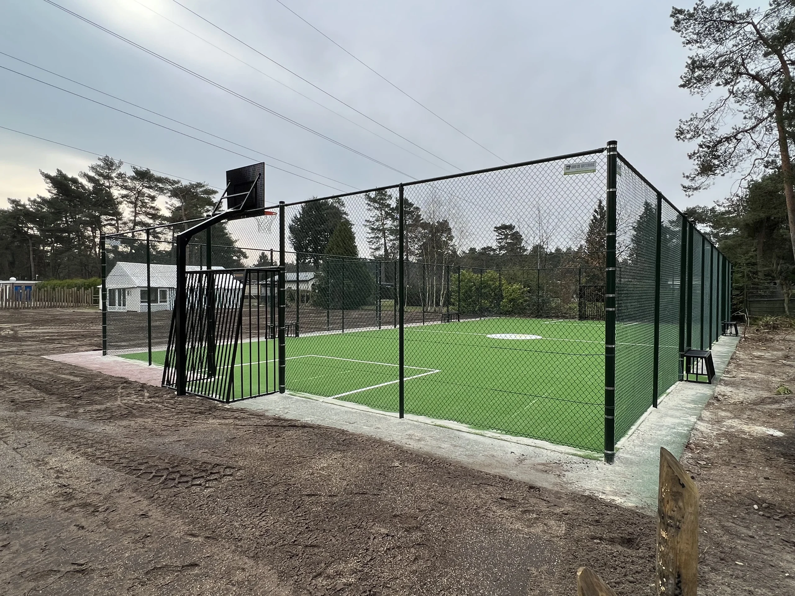 Pannaveld met groen kunstgras en hoge sportomheining