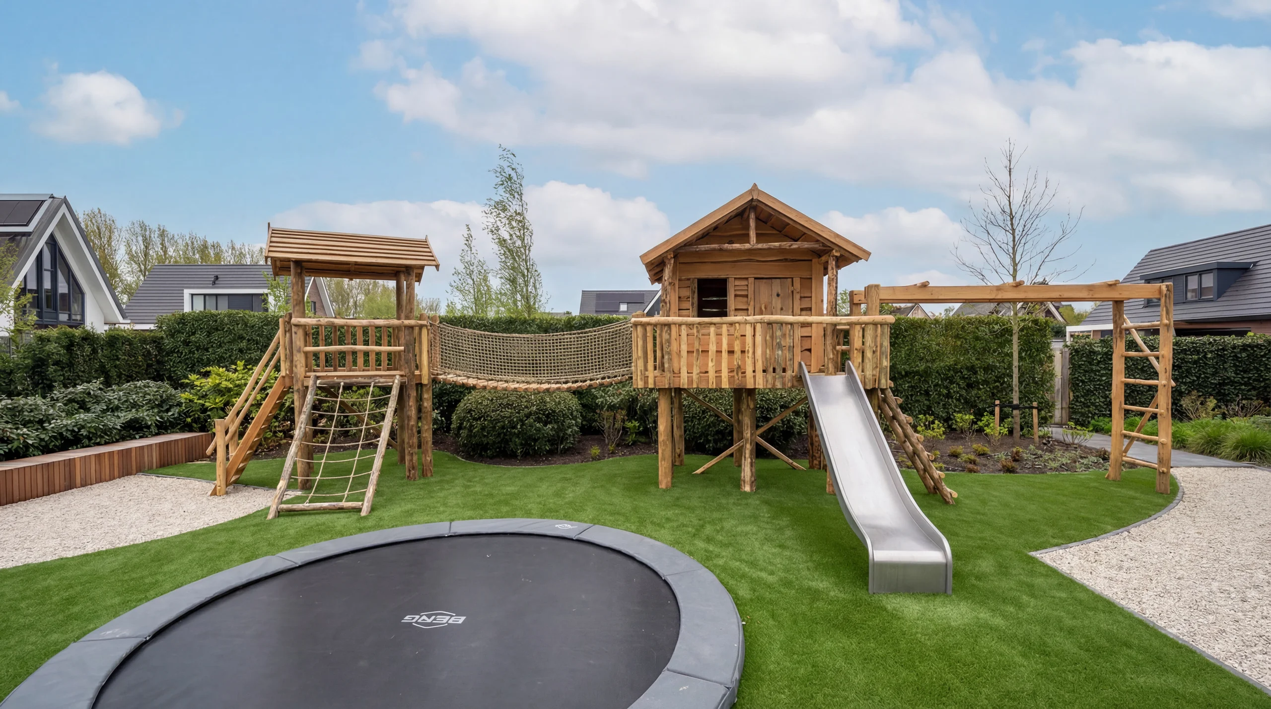 Speelplaats met kunstgras, houten speelhuis met glijbaan en een verzonken trampoline
