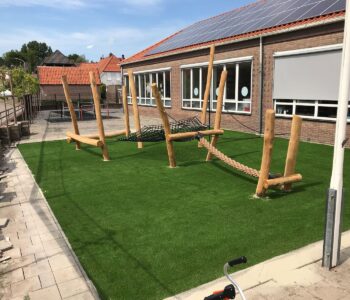 Kunstgras speelplaats met houten speeltoestellen op schoolplein