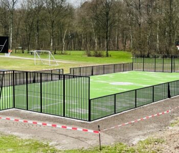 Multisportveld met kunstgras en zwarte omheining in buitenruimte